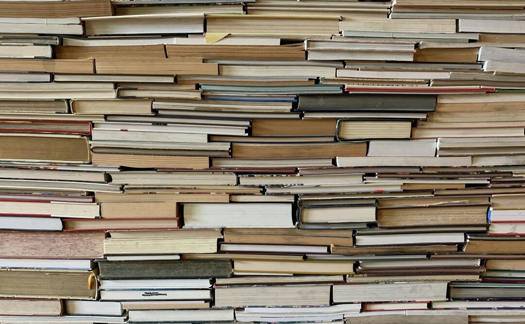 Used books stacked on their sides, mixed condition.